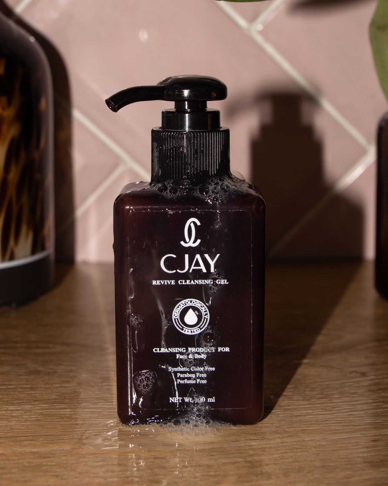 CJAY cleansing gel bottle on a wooden surface with a tiled wall background
